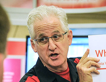 Magician working a trade show booth holding corporate logo.